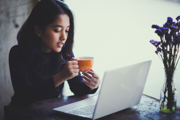 Asian  woman working with her laptop and coffee on desk, Vintage color