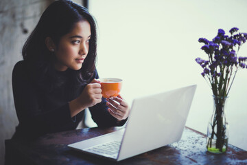 Asian  woman working with her laptop and coffee on desk, Vintage color