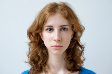 Naklejka premium A red-haired girl with freckles looks ahead. Expression of a person without emotions.