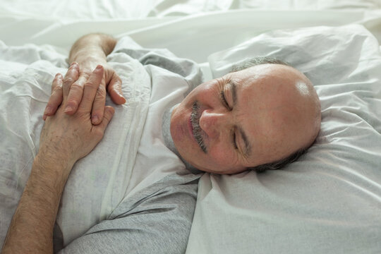 The Elderly Man Is Fast Asleep, Covered By A White Blanket. Healthy Sleep At Night