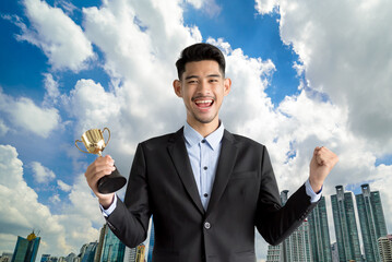 Handsome man in a suit with prize cup over a cityscape background