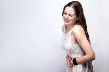 Portrait of beautiful woman with freckles and white dress and smart watch with stomach pain on...
