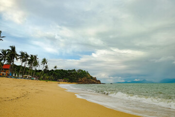 View of cloudy day at tropical beach with mountains on the horizon. Place for relaxation in authentic asian Bungalow at the Maenam beach, Koh Samui, Thailand