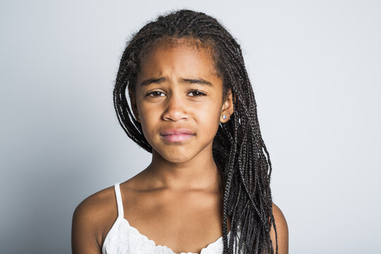 Adorable sad african little girl on studio gray background