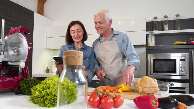 Mature couple cooking meal at home