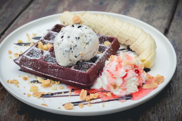 chocolate waffles with vanilla ice cream, banana, whipped cream and strawberry syrup