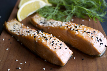 Fried salmon with sesame, lemon, dill on a wooden Board. Selective focus.