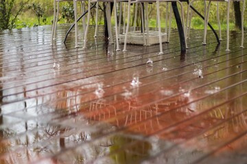 reflection of whait chairs at raining drops on wooden outside fl