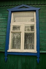 Старое окно на зелёной деревянной стене сельского дома