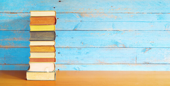 stack of books on grungy wooden planks background, panoramic, good copy space