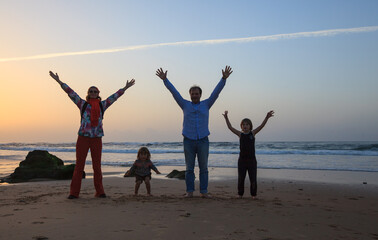 Happy family of four have fun on sandy beach in Algarve, Portugal. Mother, father and two kids boy...