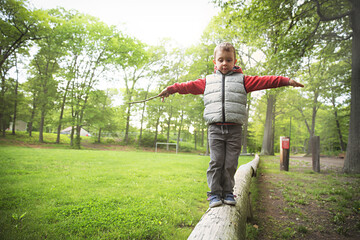 Little boy walking on a log in the park.  child on the balance beam. Copy space for your text