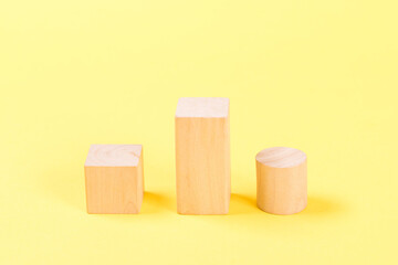 Wooden building blocks on yellow background.