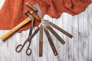 Set of cobbler tools on the light wooden background. Space for text.
