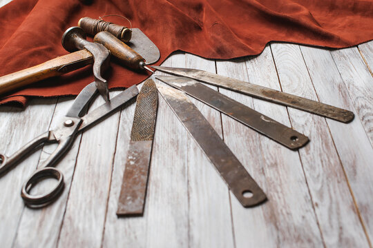 Set of cobbler tools on the light wooden background. Space for text.