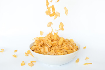 Corn flakes falling in bowl isolated on white background