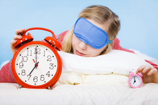 Sleeping woman wearing pajamas holding clock