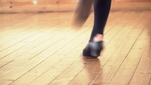 Closeup of black shoes dancing on the wooden floor
