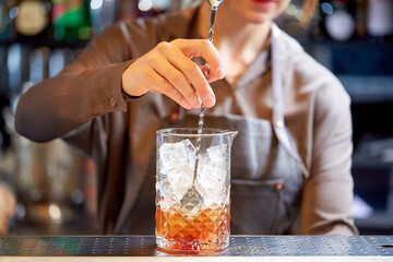 bartender with cocktail stirrer and glass at bar