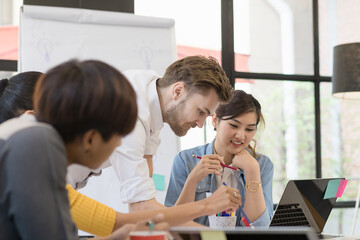Multiethnic asian group of happy business people working together, meeting and brainstorming in office. Use computer, laptop, tablet, mobile phone.