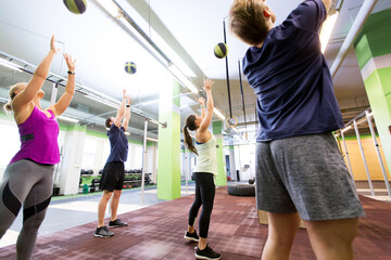 group of people with medicine ball training in gym