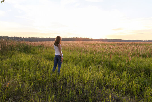 Beautiful blondie lady in field at sunset, feels happy.