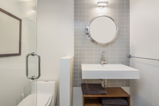 Shot of clean modern bathroom with tiled wall and round mirror