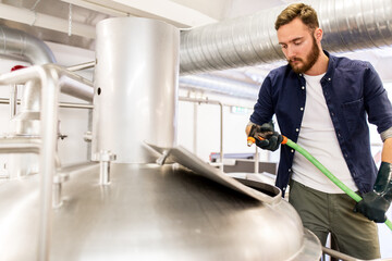man with hose working at craft beer brewery kettle