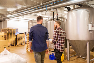 men with clipboard at craft brewery or beer plant