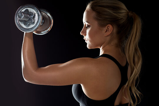 young sporty woman exercising with dumbbell
