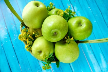 
Fresh green apples with flowers in basket