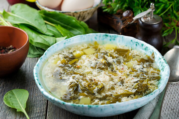 Simple vegetarian soup made of sorrel, potatoes and beaten eggs on a light background. Selective...