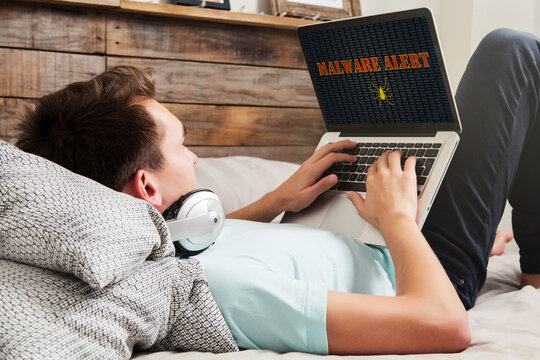 Malware alert in a laptop computer being used by man at home.