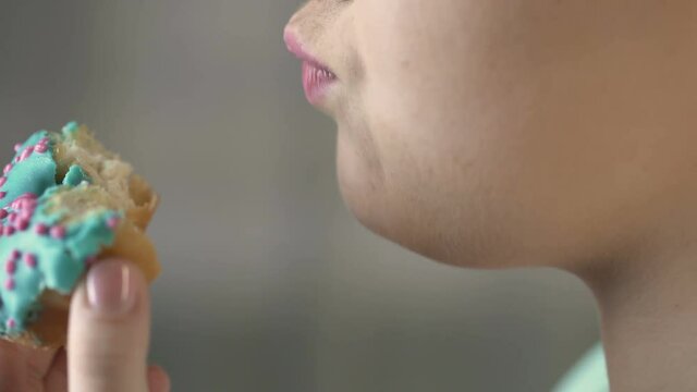 Closeup video of chubby woman eating doughnut with appetite, unhealthy food