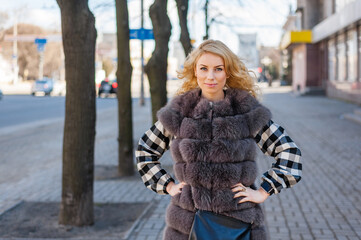 Young girl in a fur coat posing in the city