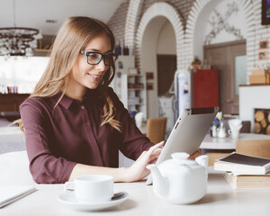 Concentrated at work. Confident young woman in smart casual wear working on laptop while sitting near window in creative office or cafe