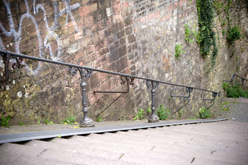 Treppe mit Fahrradschiene / Eine steile Treppe an einer Stadtmauer mit einem Eisengeländer sowie einer Fahrradschiene.