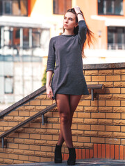 Young attractive athletic caucasian girl or woman in striped dress over city background