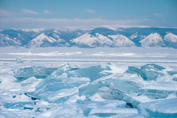 Blue ice on the frozen lake Baikal with mountain background