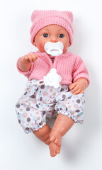 Toy doll child, in pink blouse with pacifier on isolated background