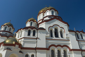 Fototapeta na wymiar The building of the new Athos monastery with glittering domes on the blue sky background