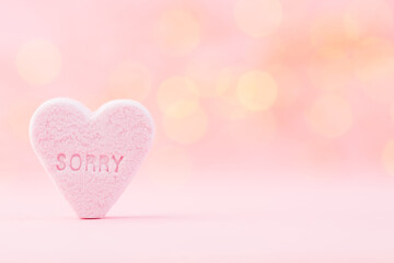 Pastel colored candy hearts in a bokeh background.