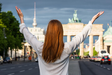 Young woman greetings Berlin in her life with outstretched hands. She is happy.