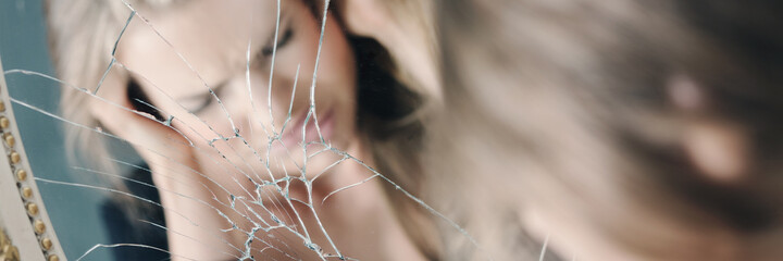 Stressed woman in broken mirror