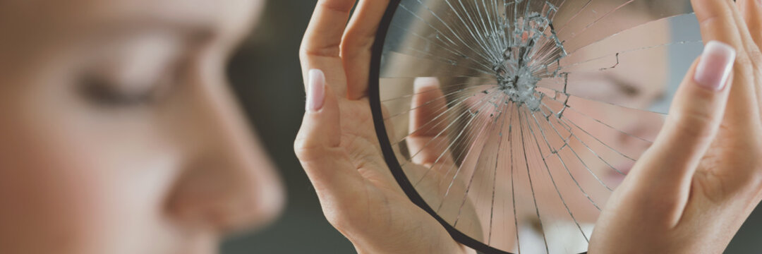 Woman holding broken mirror