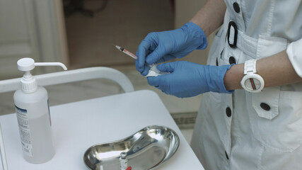 Professional beautician gaining material into the syringe for injection into the skin