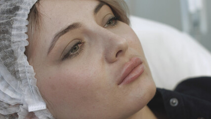Patient looking at herself in the mirror after the lip augmentation procedure