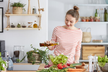 Woman adding olive to a salad