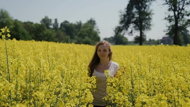 Young Woman Running through Yellow Field Touching Flowers HD