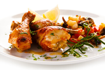 Grilled chicken drumsticks with vegetables on white background